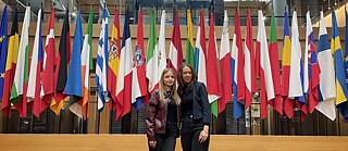 Zwei Frauen im EU Parlament vor den Flaggen